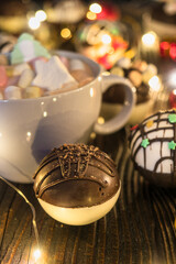 Chocolate bomb with cocoa powder and mini marshmallow to prepare a fragrant hot drink. On dark wooden background.