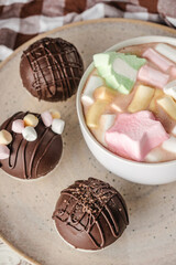 Chocolate bomb with cocoa powder and mini marshmallow to prepare a fragrant hot drink. On white wooden background.