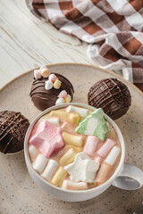 Chocolate bomb with cocoa powder and mini marshmallow to prepare a fragrant hot drink. On white wooden background.