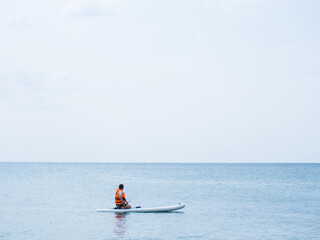 An athlete trains on a board, swims in the sea and rows. Surfing on a surfboard as a hobby.