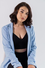 Obraz premium Beautiful young girl in black trousers and a blue jacket on a white background. Portrait of a beautiful young woman