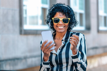 woman with headphones and mobile phone smiling with yellow sunglasses
