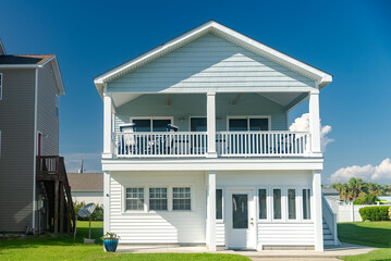 two-story cottage by the Atlantic Ocean. Palm trees and blue sky.