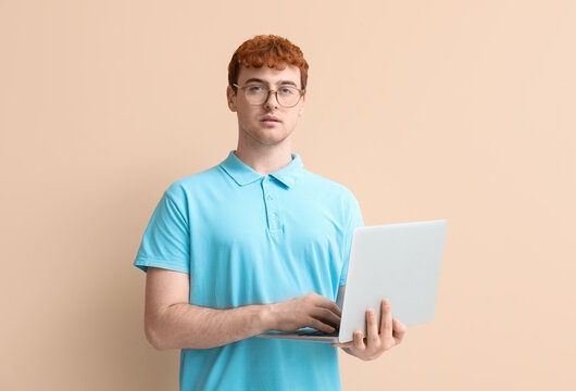 Male programmer working with laptop on beige background