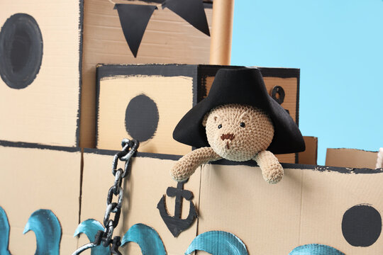 Pirate cardboard ship with toy bear on blue background