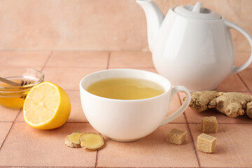 Cup of ginger tea and bowl with honey on pink tile table