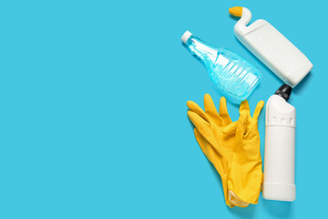 Bottles of detergent and gloves on blue background