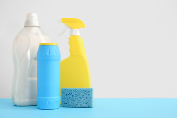 Detergents and sponge for cleaning on blue table against white background