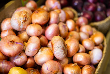 Straw basket full of common onions set along the counter in open-air vegetable market