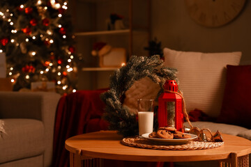 Christmas cookies with glass of milk and decor on table in room at night, closeup