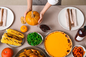 Woman with tasty food on dining table set for Thanksgiving Day, top view