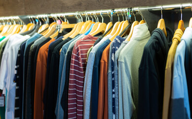 Assortment of summer and autumn clothing in modern garment store interior