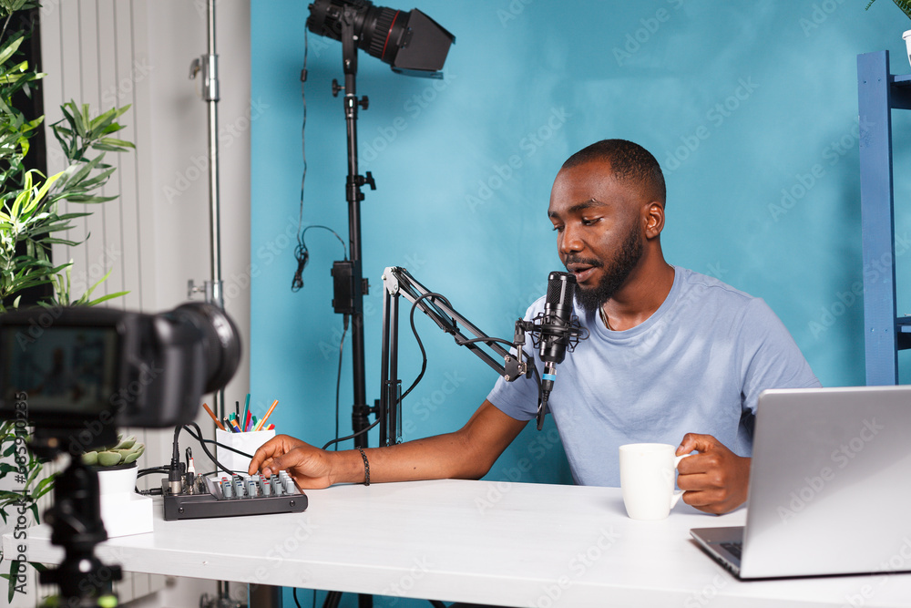 Poster african american blogger creating professional video content with camera and volume controller. vlog