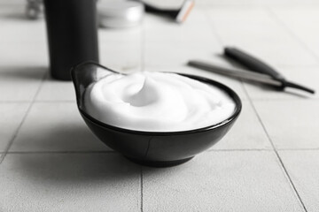 Set of shaving accessories on white tile background