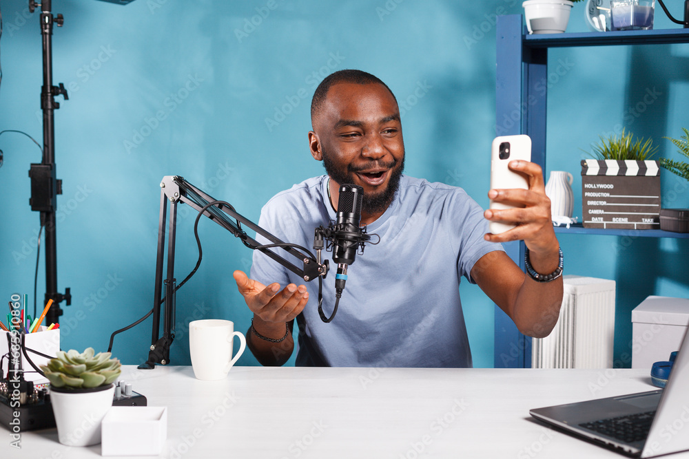 Poster blogger creating engaging content with smartphone and speaking to subscribers. smiling african ameri