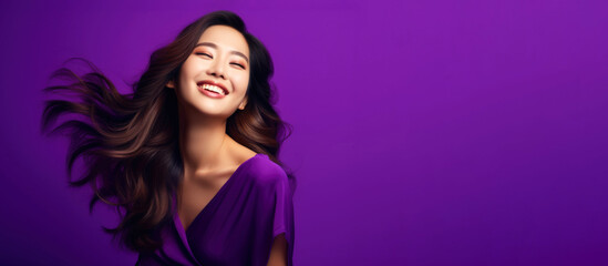 Portrait of a beautiful young Asian woman smiling on a purple background with flowing long shiny wavy hair
