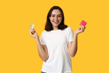 Young woman with condoms on yellow background. Safe sex concept