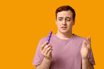 Emotional young man with vibrator on yellow background