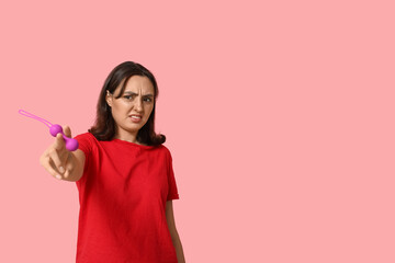 Emotional young woman with anal plug on pink background