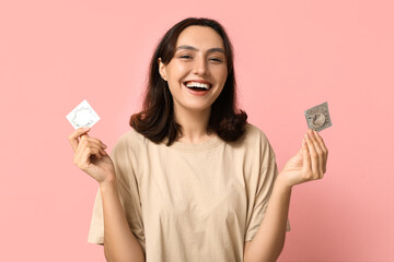 Young woman with condoms on pink background. Safe sex concept