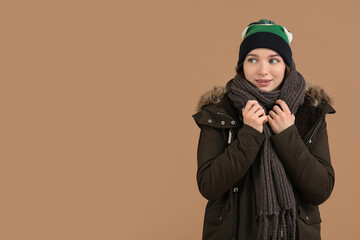 Young woman in winter clothes on brown background