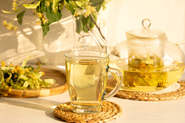 Linden flower tea in the transparent glass cup with tea spoon on a background 