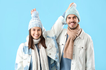 Loving couple in winter clothes on blue background