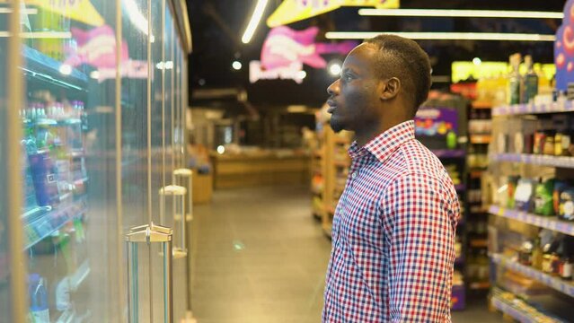 African american man doing shopping at supermarket while buying cold fizzy drink