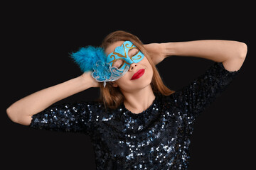Beautiful young woman in blue carnival mask on black background © Pixel-Shot