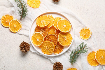 Plate of dried orange slices with pine cones and fir branches on white background
