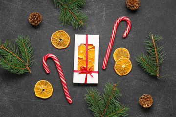 Gift box with dried orange slices and Christmas candy canes on black background