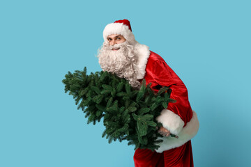 Young man in Santa Claus costume with Christmas tree on blue background