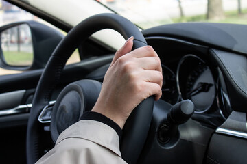 hands of a young girl on a car steering wheel