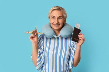 Mature woman with wooden airplane and passport on blue background. Travel concept
