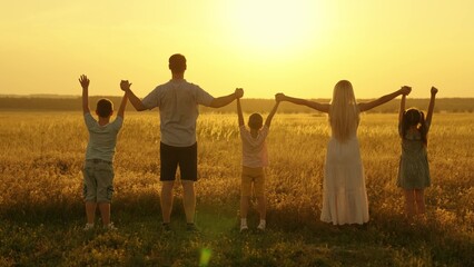 Happy family raise their hands outdoor at sunset. Teamwork of group of people, walk in park. Child mom dad walking holding hands. Group prayer sun. Family holiday. Parents child holding hands together