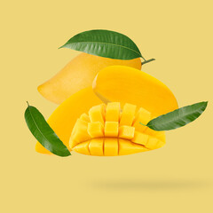 Flying Fresh ripe mango with leaves on yellow background. Food levitation concept