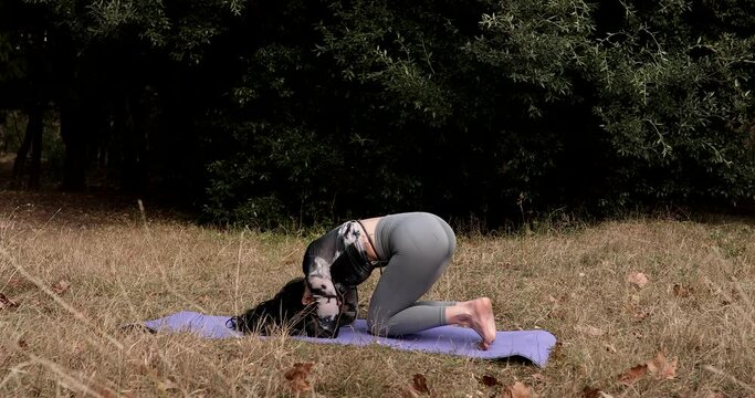 Active woman does headstand yoga practice in park. Iyengar yoga practitioner on balance pose outdoors. Healthy lifestyle, wellness concepts.