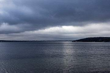 A dark blue lake on a cold, wintery day with dark rain clouds.