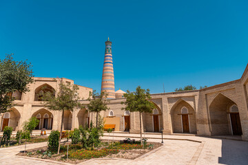 Idyllic view on Islam-Khoja minaret and walking Uzbeks in Khiva old city
