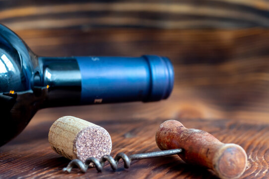 Wine cork, corkscrew, wine bottle close-up. On a wooden background
