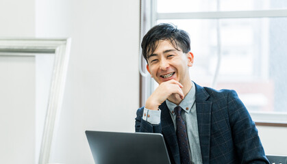 パソコンを使う笑顔の男性ビジネスマン