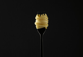 Fork with tasty pasta on black background