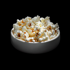 Fresh popcorn in a white bowl on a black background. Warm, delicious tone. Isolate. Selective focus, close-up.
