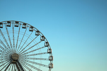 Big Ferris wheel against light blue sky. Space for text