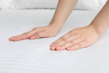 Woman touching white soft mattress on bed, closeup view