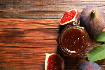 Jar of tasty sweet jam and fresh figs on wooden table, flat lay. Space for text