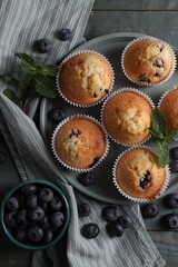 Delicious sweet muffins with blueberries and mint on light blue wooden table, flat lay