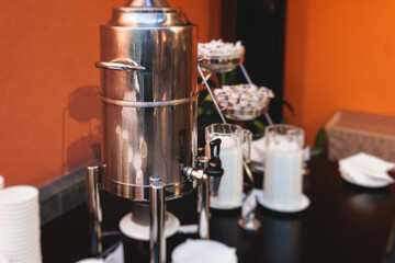 Set of coffee break lunch in the hotel restaurant during conference meeting, with tea and coffee catering, decorated banquet table with white tableware and metal tea maker machine boiler
