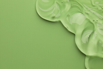 Clear cosmetic gel on light green background, top view. Space for text