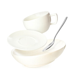 Clean dishes, cup and spoon falling on white background